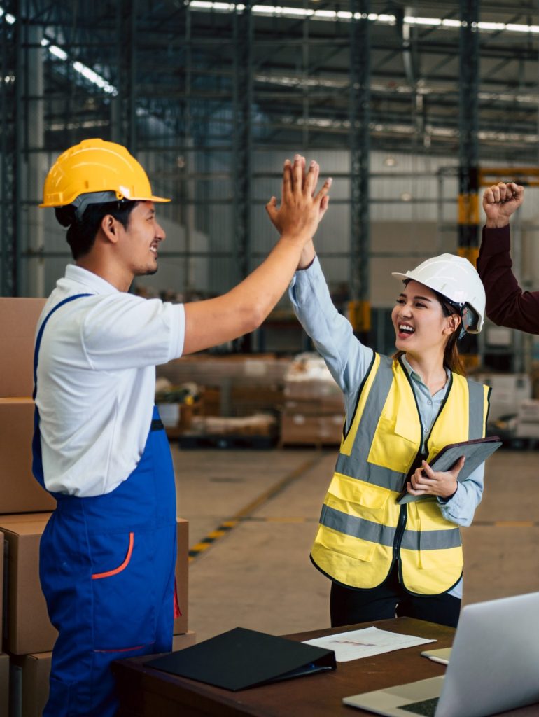 Group of engineers, industrial workers congratulation each other with high five gesture after success of meeting or finishing project in the factory.